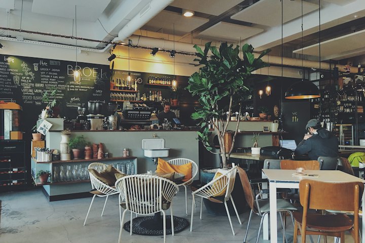 A café with wooden tables surrounded by plants